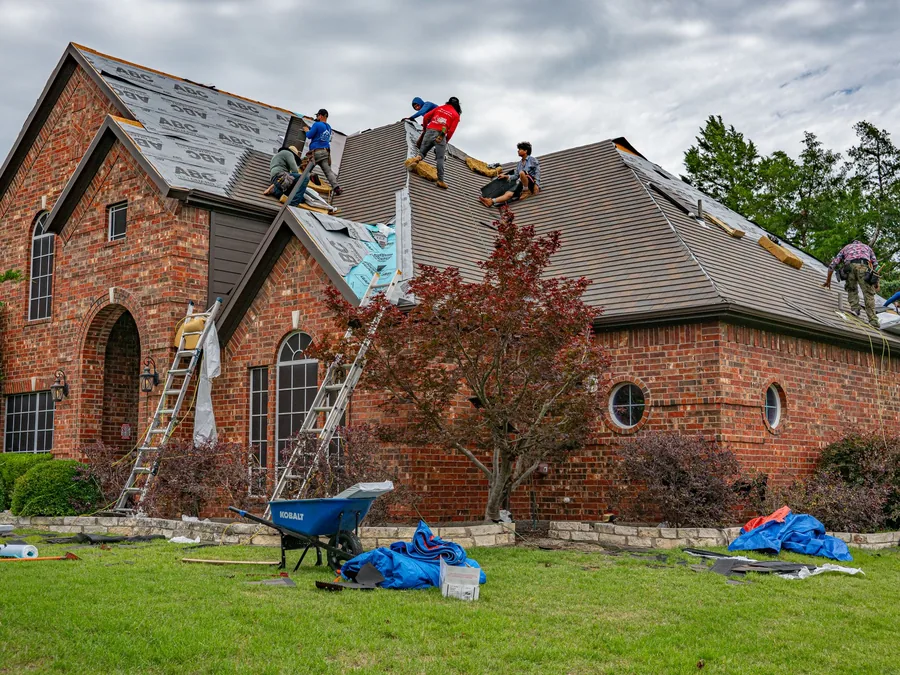 Roofers replacing the roof on a brick house